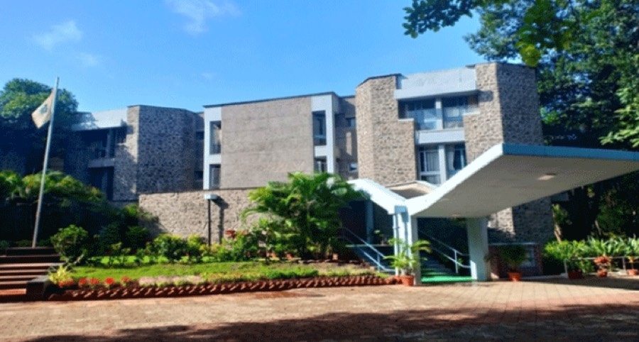 The National Institute of Bank Management campus at Kondhwe Khurd, Pune — a stone-clad academic block behind a canopied entrance and landscaped forecourt